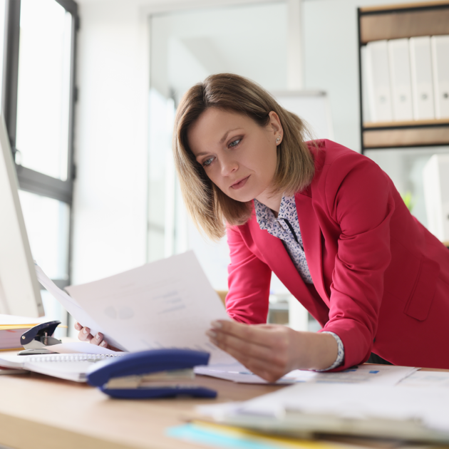 Business woman leaning on a table, comparing documents.