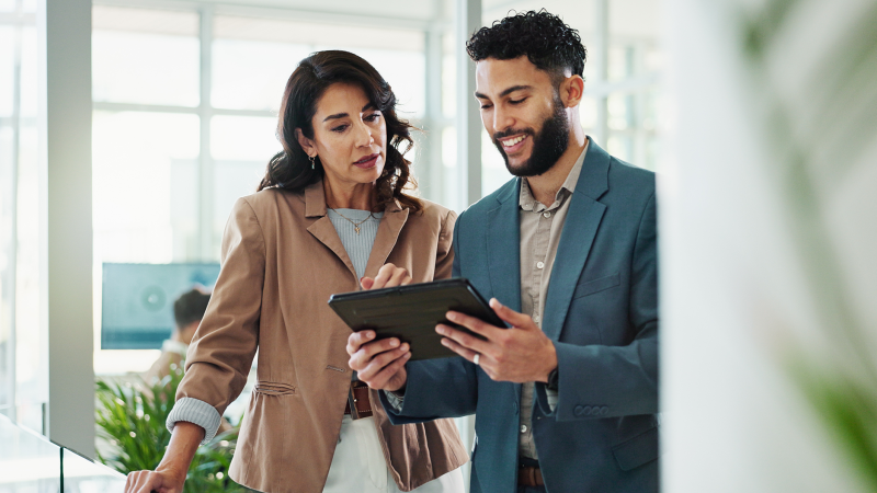 Business people in an office review research on a tablet.